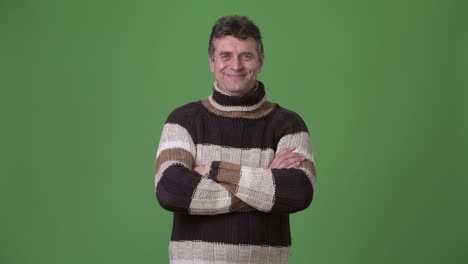 mature handsome man wearing turtleneck sweater against green background