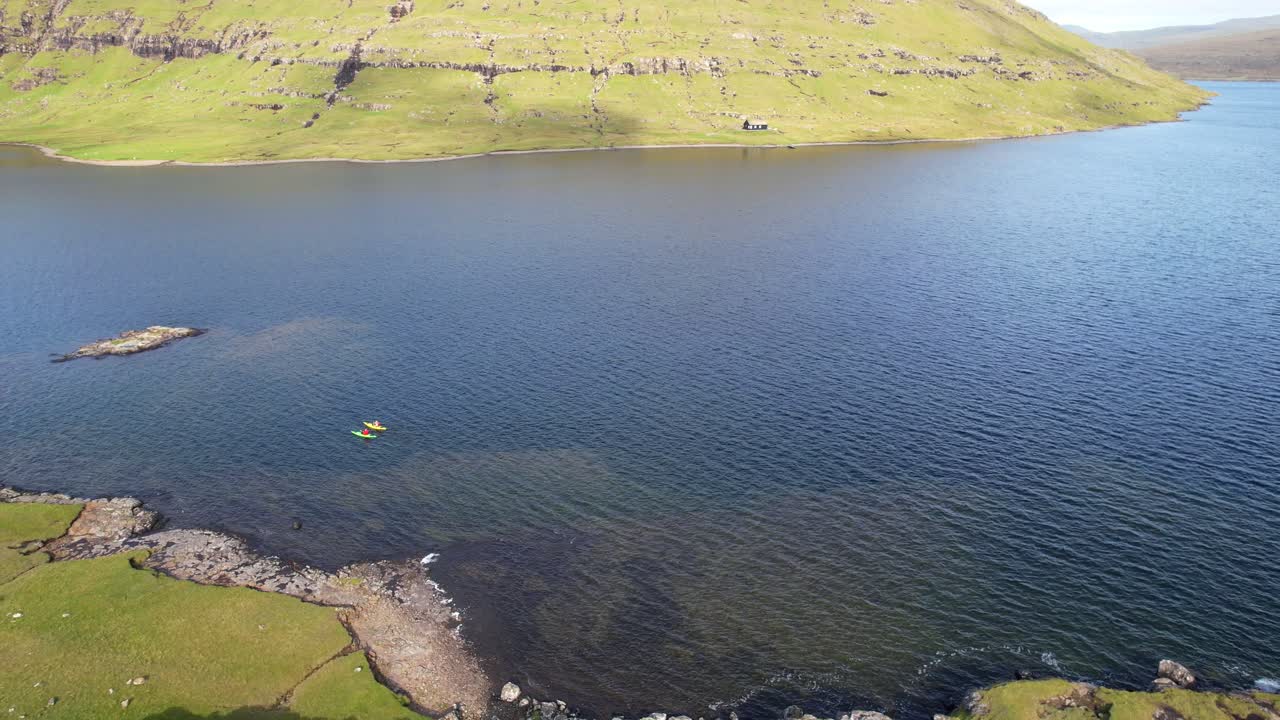 페로 제도 바가르 섬 에 있는 소르바그스바트 호수 에서 카야크 를 타고 있는 두 사람 의 항공 뒷면 촬영