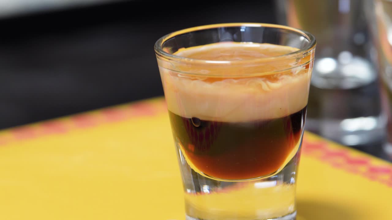 Female Hand Picks Up A B52 Shot Glass Or Cocktail Drink On The Table. closeup