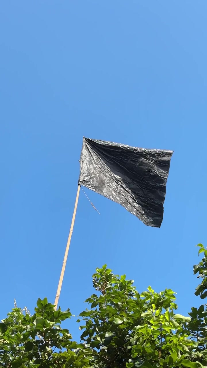 Bandera de bolsa de plástico negra ondeando al viento contra el cielo azul