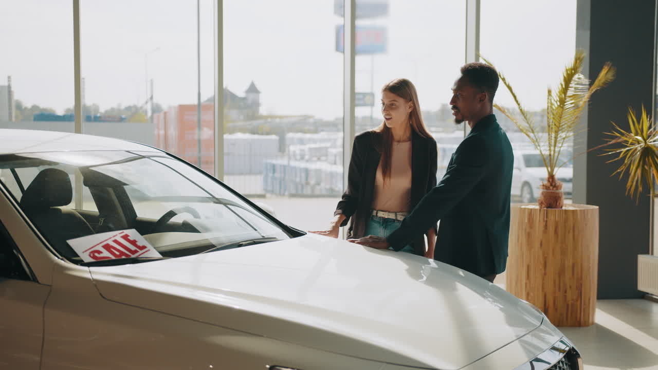 una pareja mirando un coche a la venta en una sala de exposiciones