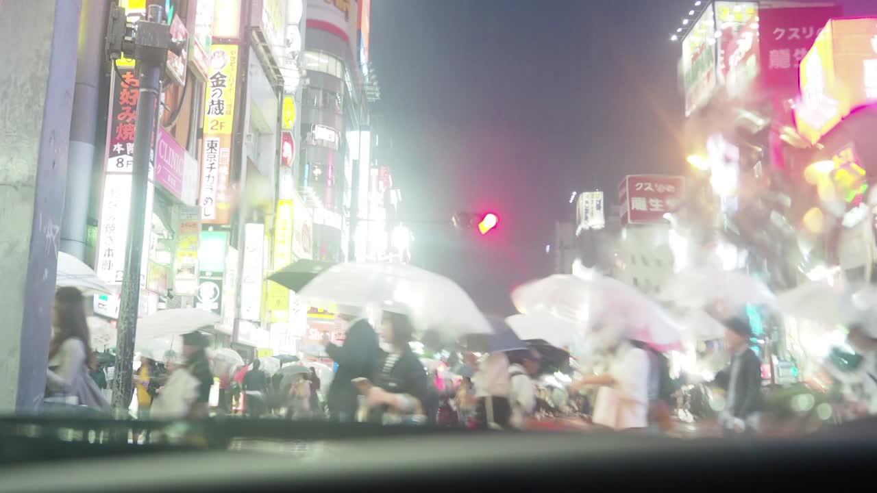 비가 내리는 도쿄 신주쿠의 교차로를 건너는 사람들