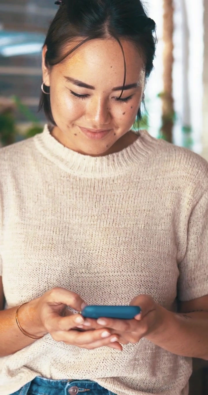 Giovane donna che usa lo smartphone in un ambiente interno luminoso