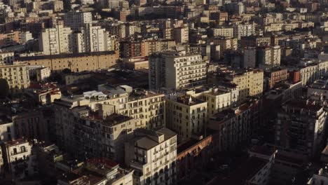 aerial view showing crowded apartment block houses in naples city build on hill during sunset time - tilt up movement