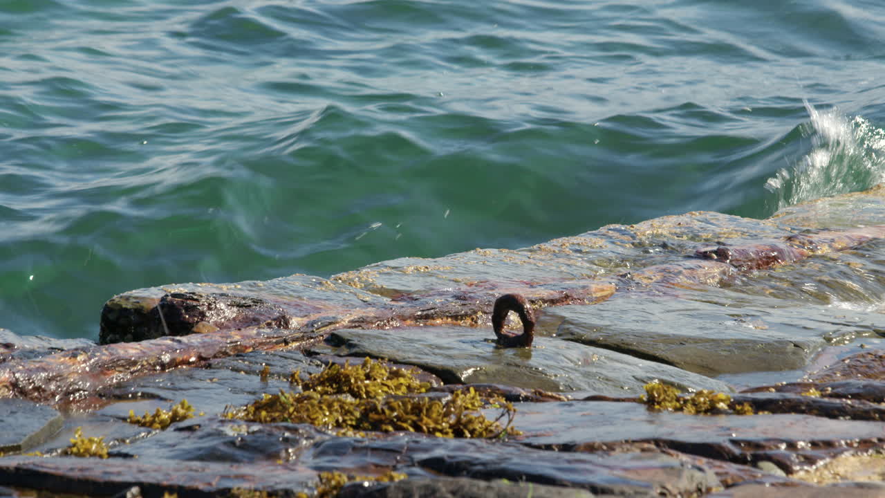 Waves Crashing on Rocky Shore with Rusty Metal Ring