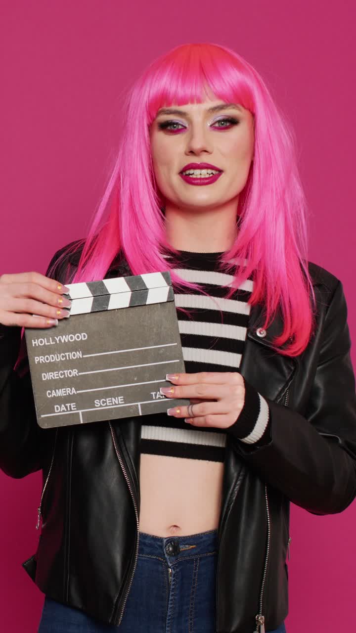 Pystyvideo: Kaunis ja cool tyttö näyttää kuvauslippua studiokamerassa