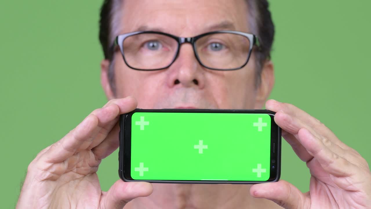 Senior handsome man showing phone and thinking