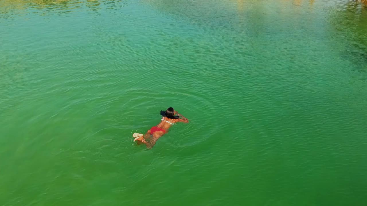 impresionante toma de drone de una modelo nadando en un lago salado con tonos verdosos