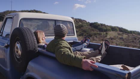 a couple sits in the back of a pickup truck parked on a rural road