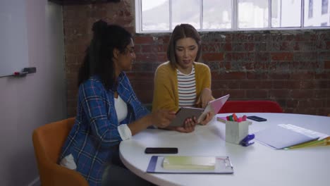 Diverse-female-business-colleagues-in-discussion-at-work-looking-at-digital-tablets