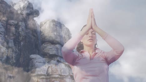 Animation-of-clouds-over-caucasian-woman-practicing-yoga-and-meditating