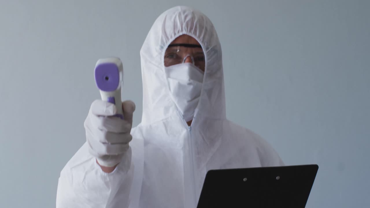 trabajador de la salud con ropa de protección con una pistola de temperatura