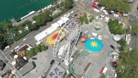 Orbiting-aerial-drone-shot-flying-around-amusement-park-ferris-wheel-with-the-city-of-Zürich,-Switzerland-in-the-background-during-Zürichfest