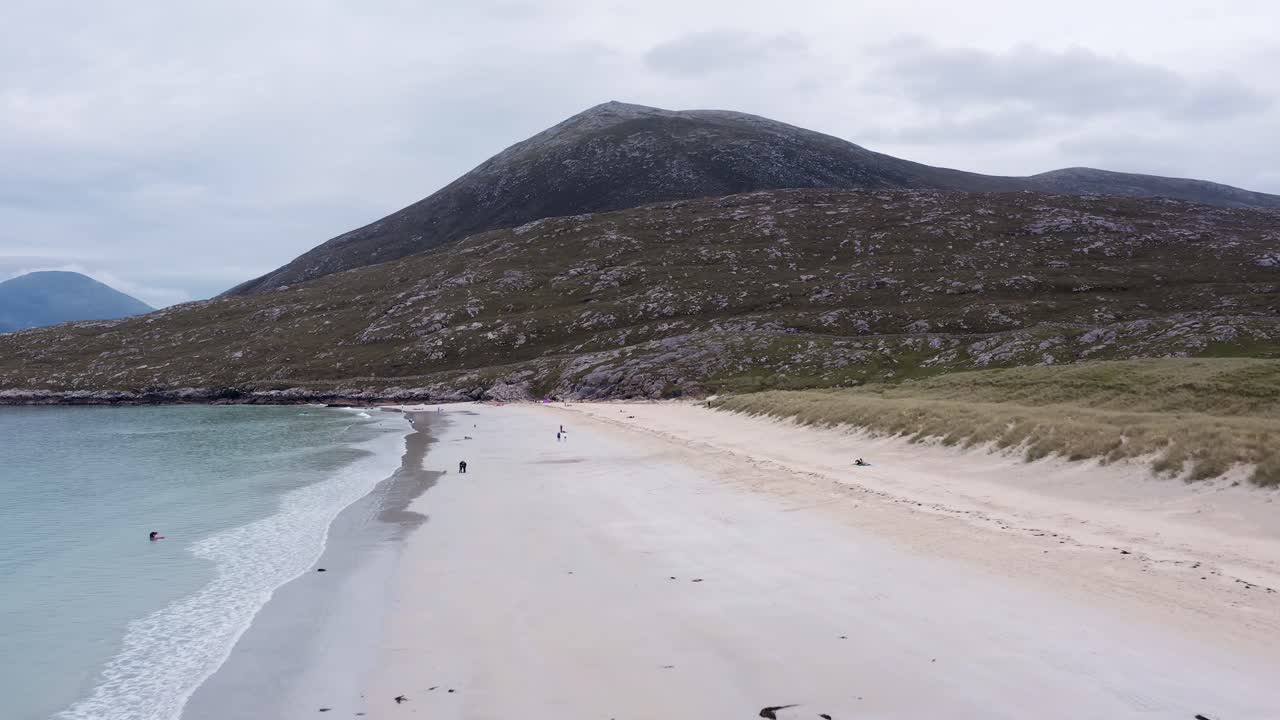 화창한 여름날 luskentyre 해변의 역동적인 드론 샷, 사람들이 모래를 따라 걷는 모습
