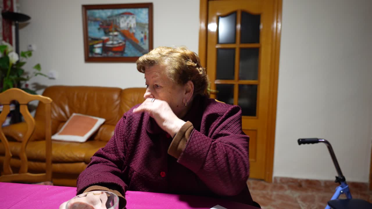 할머니의 중간 클로즈업 시니어 여성이 테이블 건너편에 있는 누군가와 진지하게 이야기하고 있습니다.