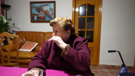 primer plano medio de la abuela una mujer mayor hablando seriamente con alguien al otro lado de la mesa