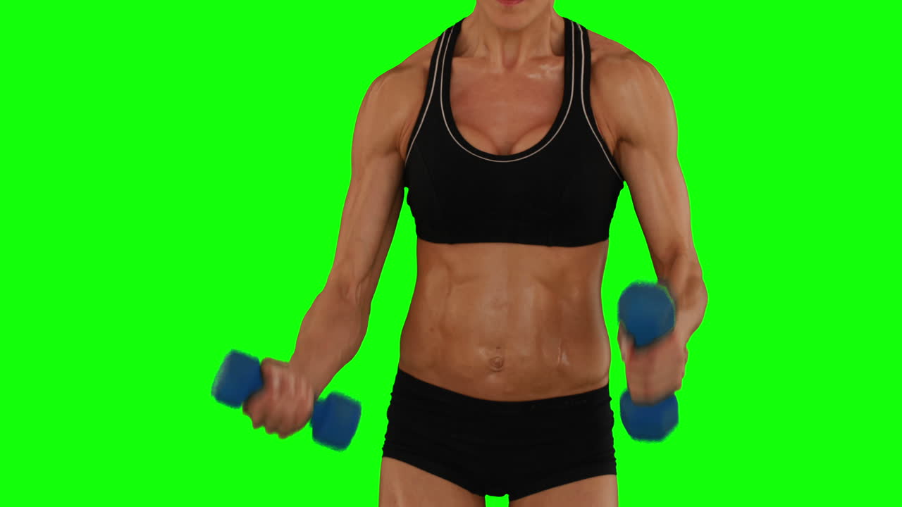 Sehr fitte Frau hebt Hanteln in schwarzem Sport-BH und Shorts