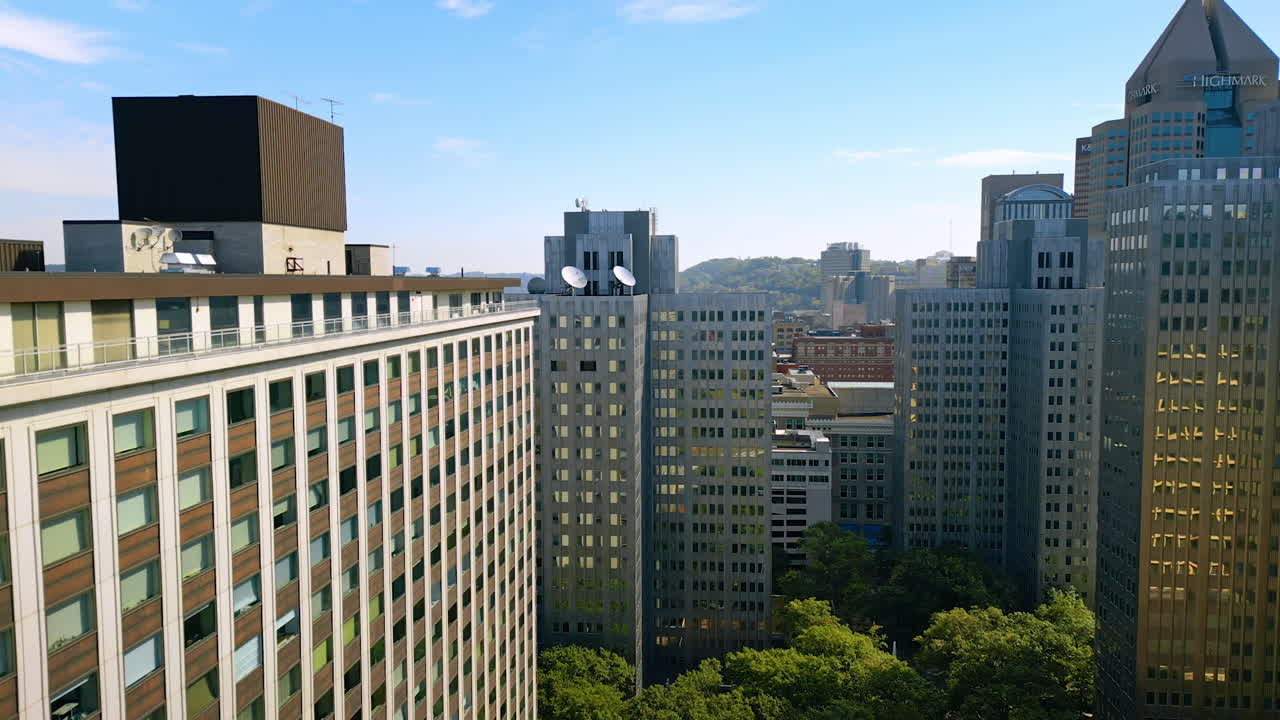 Pittsburgh, USA, 2 August 2025: Rising to the tops of the high-rise buildings similar in design. Lots of greenery grows below. Architecture of Pittsburg, Pennsylvania, USA