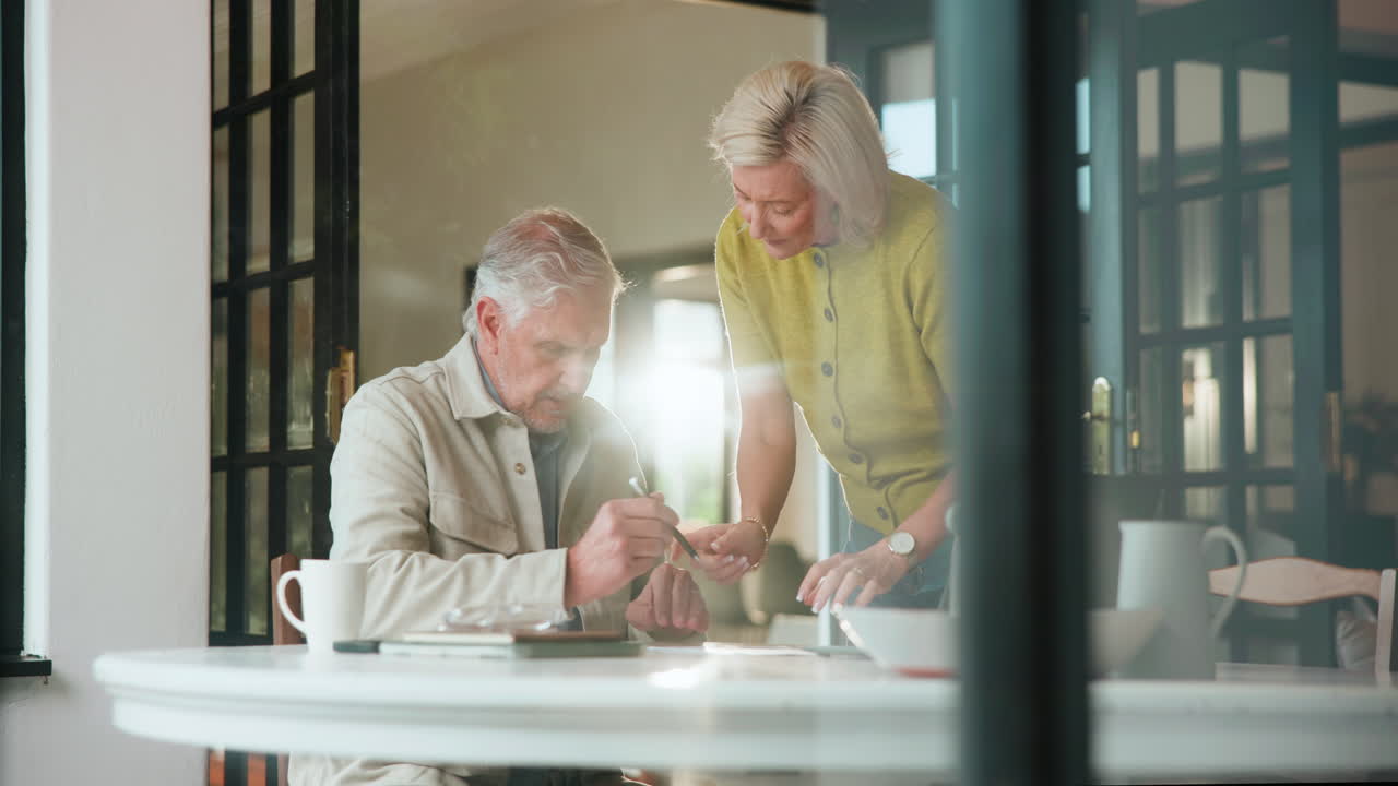 Senior Couple Reviewing Documents and Signing Paperwork at Home