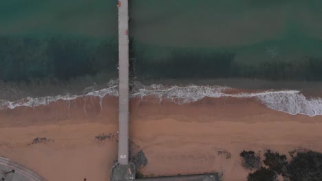 beautiful aerial top-down static shot of empty pier from beach to sea