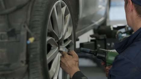 mechanic changing car wheel with impact wrench