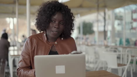 Focused-young-woman-using-laptop-and-answering-phone-call