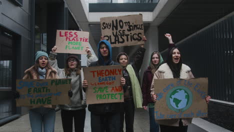 grupo multicultural de jóvenes activistas con pancartas de cartón que protestan contra el cambio climático mirando la cámara