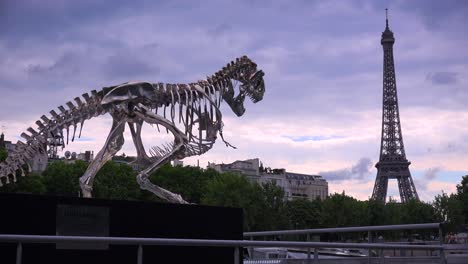 a dinosaur sculpture stands with the eiffel tower background