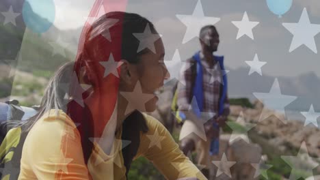 Animation-of-american-flag-over-smiling-diverse-couple-hiking-in-mountains