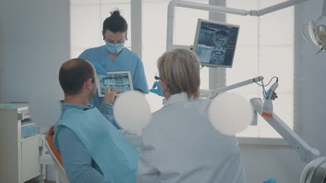 dentistry team showing teeth x ray scan to patient with toothache