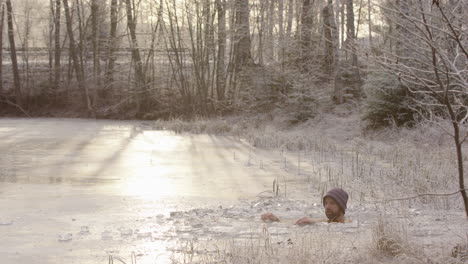 a cyclist rides past r2l as the ice bather sits in freezing cold water, golden light