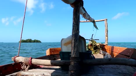 static shot from a wooden rural boat sailing towards an island paradise in the middle of the ocean