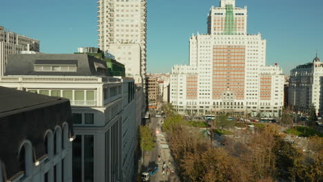 Forwards-elevated-fly-along-buildings-at-Plaza-de-Espana-with-historic-tall-skyscrapers.