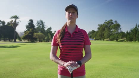 retrato de una jugadora de golf caucásica sonriendo mientras está de pie en el campo de golf