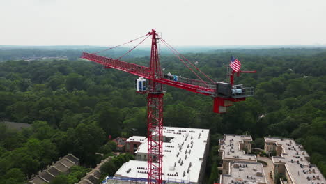 orbit shot around red tower crane above construction site of modern multistorey building in urban borough