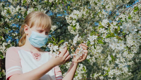 un niño triste con una máscara está admirando los problemas de alergia de un árbol en flor