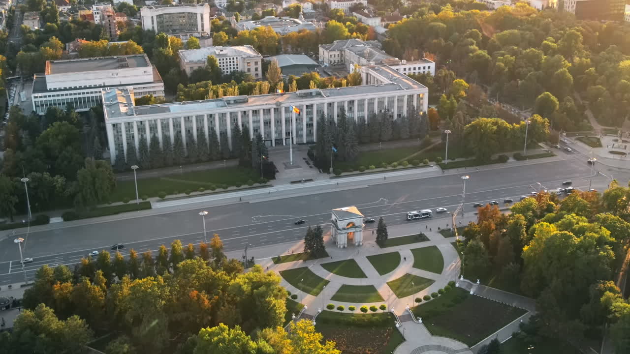Aerial drone view of Chisinau downtown at sunset. Panorama view of central park, Cathedral, bell tower, a lot of greenery, walking people, buildings, Goverment. Moldova