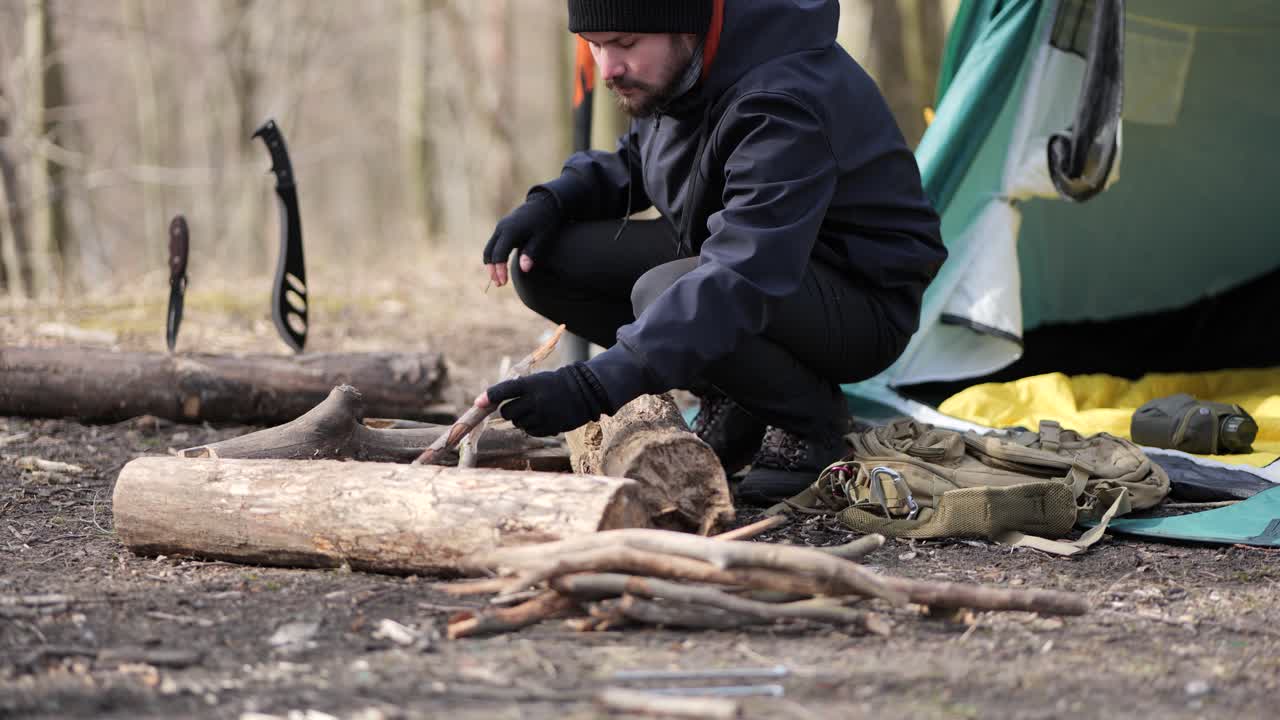 одинокий путник разводит костер возле палатки в лесу в осенний день