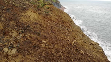 disparo aéreo hacia adelante volando sobre escombros de deslizamiento de tierra en seatown suroeste de inglaterra