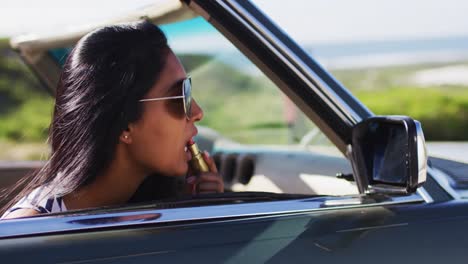 Mujer-Afroamericana-Aplicando-Lápiz-Labial-Mientras-Mira-En-El-Espejo-Del-Auto-Convertible