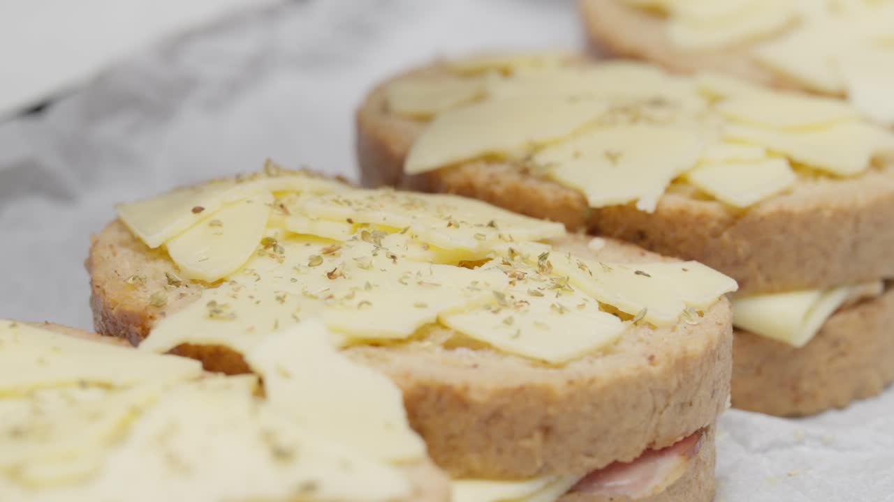 Close-up of dried oregano being sprinkled on a sandwich during food preparation