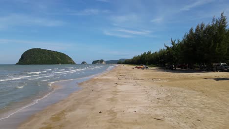 Reverse-aerial-footage-at-a-low-altitude-revealing-a-speedboat,-fishing-boat,-beachfront,-islands,-Dolphin-Bay,-Sam-Roi-Yot-National-Park,-Prachuap-Khiri-Khan,-Thailand