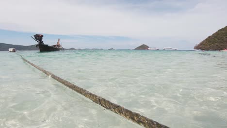 Water-level-view-of-lengthy-rope-mooring-rural-fishing-boat-in-Koh-Hey---Wide-ground-level-detail-push-in-shot