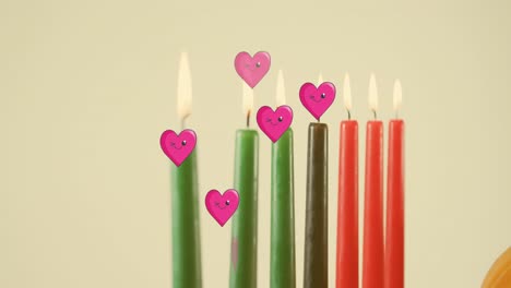 Animation-of-pink-hearts-over-kwanzaa-candles-on-grey-background