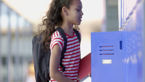 biracial girl with curly hair stands by school lockers