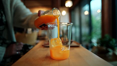 woman pouring orange juice at a cozy cafe