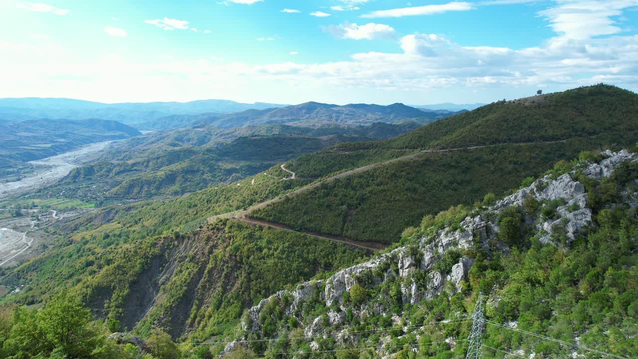 Panoramic shot (side pan, aerial tracking) of the vast, forest-covered mountainous landscape in Kabashi, Albania. The video focuses on untouched natural beauty, geography, and topography