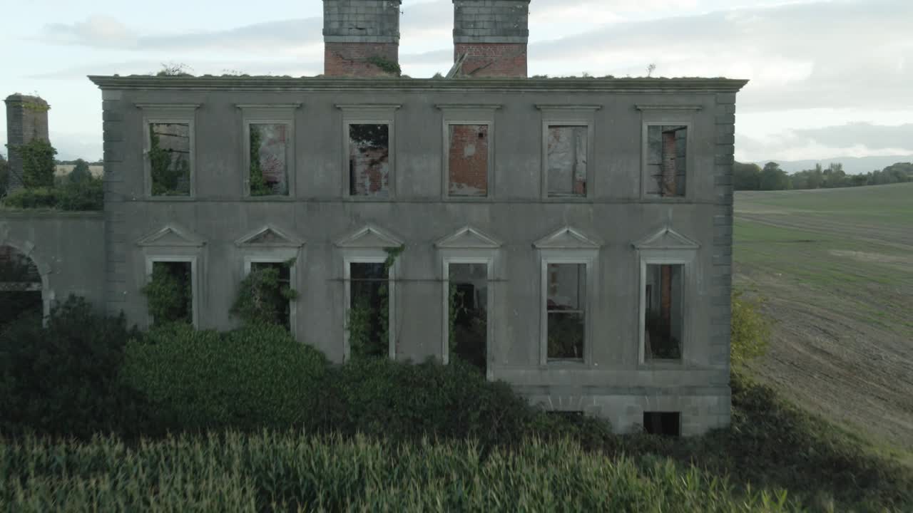 Abandoned Stephenstown House in Ireland overlooks a large cornfield under cloudy skies