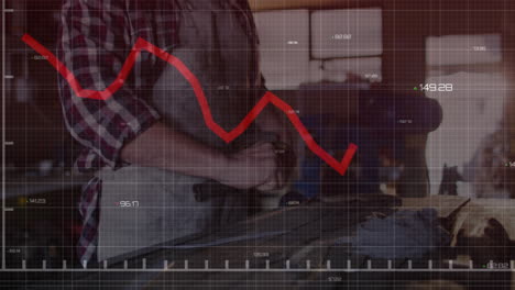 woodworker operating belt sander in workshop, showing red data graphs tracking manufacturing output