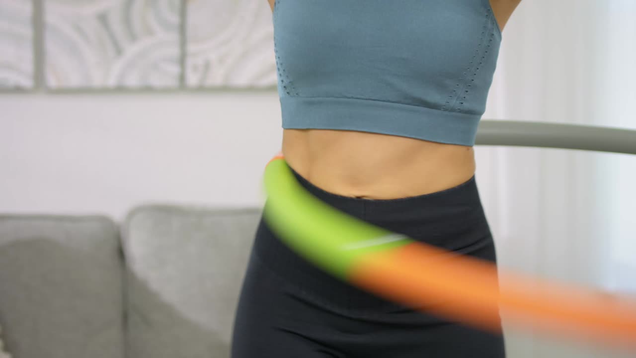 A beautiful girl with a nice body twists a big hoop in the waist